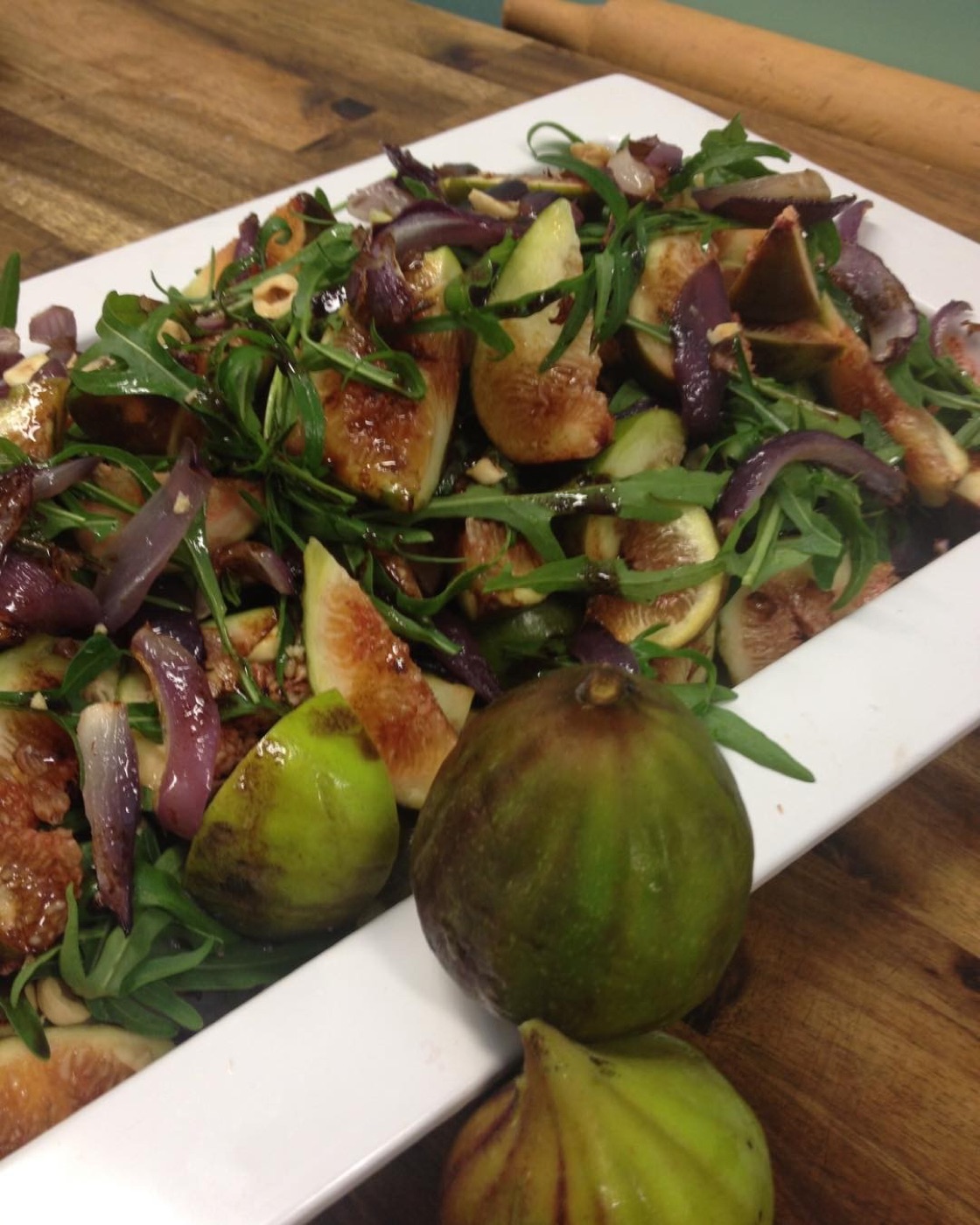 Fresh fig salad with red onion and rocket on a long white plate