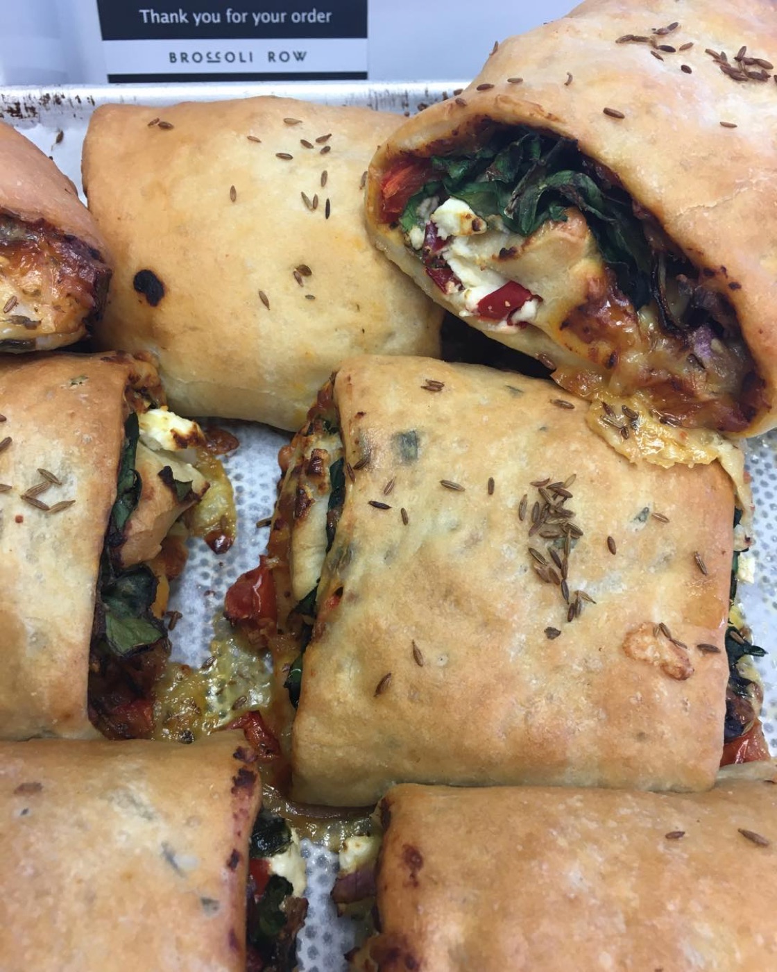 Baked spinach and red pepper involtini scattered with cumin seed